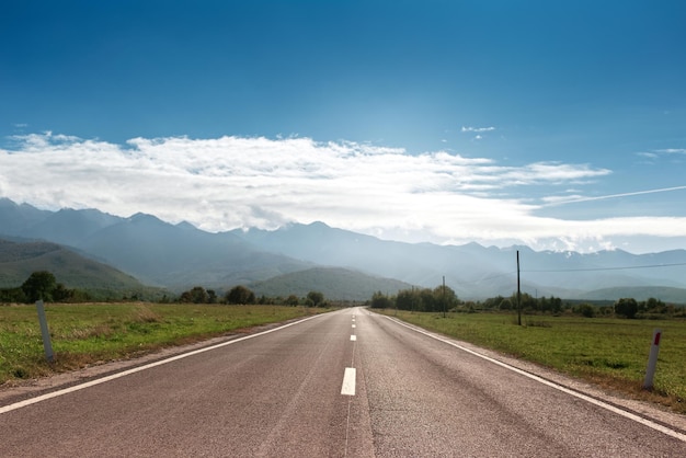 Perspective straight of asphalting road on background of blue sky and mountains