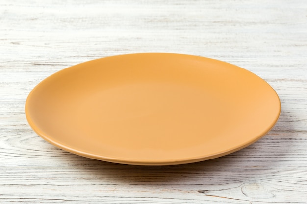 Perspective view. Empty orange matte dish for dinner on white wooden 