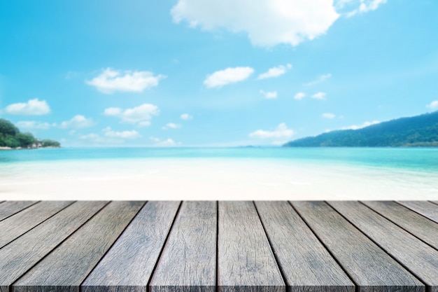 Perspective wooden table on top over blur sea in sunny day background.