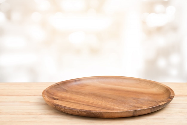 Perspective wooden table and wooden tray on top over blur bokeh light background