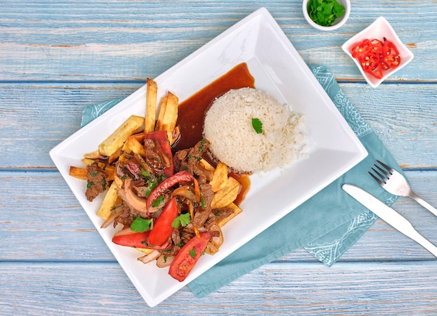 Photo peruvian food lomo saltado a salted beef with tomatoes onion fried potatoes and rice