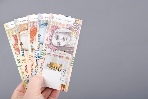 Peruvian money in the hand on a gray background