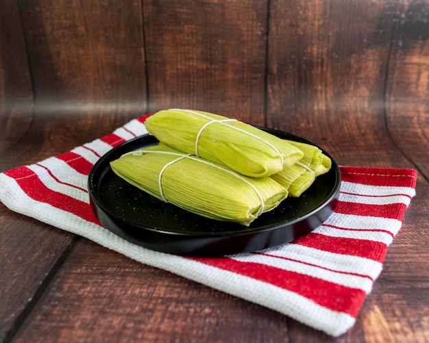 Photo peruvian sweet humitas served on a black plane on a wooden background detail shot green tamale