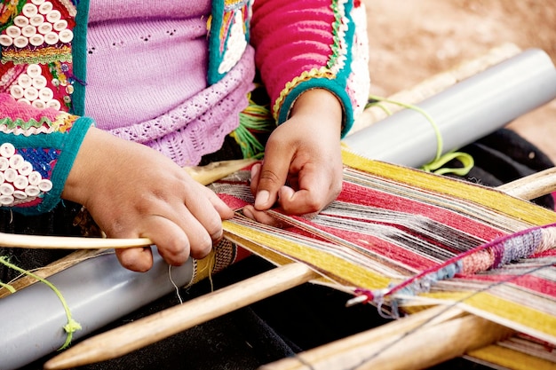 Peruvian woman's hands close up weaving colorful fabric in Cusco, Peru