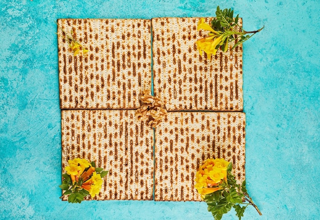 Pesach celebration concept Jewish holiday Pesach Four square folded matzahs with flowers View from above Flat layout