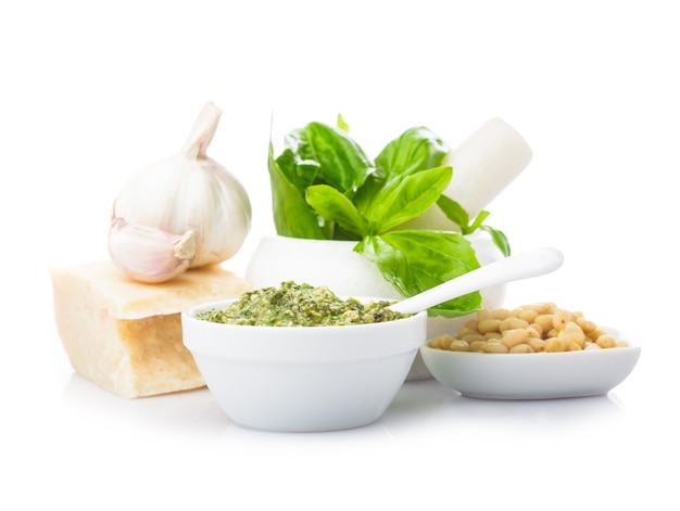 Pesto sauce ingredients: fresh green basil, parmesan, pine nuts and garlic. On white