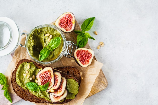 Pesto sauce sandwich with figs on rye bread, top view.