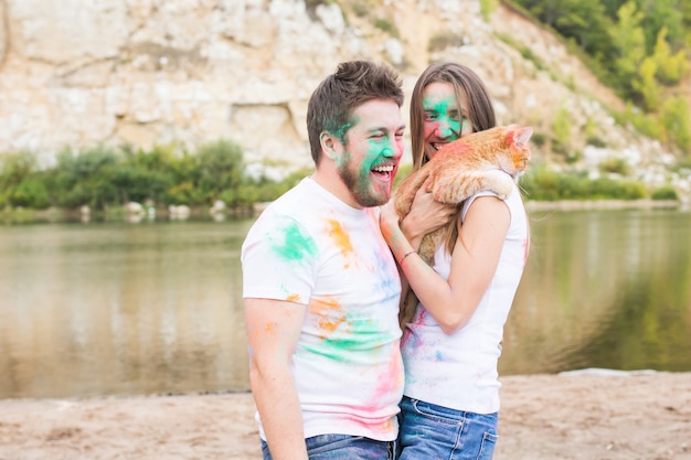 Pet, summer tourism, festival holi and nature concept - funny man and woman with cat on natural background.