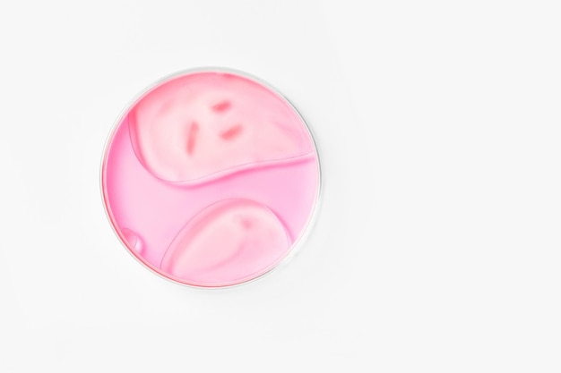 Petri dish on a light background With pink liquid Water stains oil drops Glassware study Chemical elements