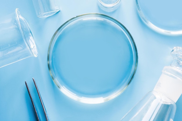 Petri dish with liquids and pincers in laboratory on blue Fluid testing