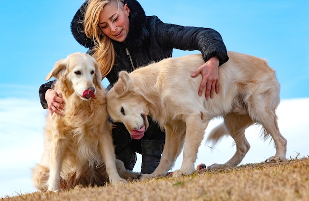 Pets and dogs. Blonde girl smiling and enjoying her pet dog in the park. Golden retriever.