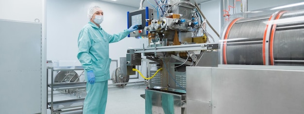 Pharmaceutical technician in sterile environment working with equipment at pharmacy industry