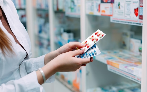 Pharmacist holding medicine box and capsule packs in pharmacy drugstore.