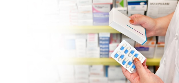 Pharmacist holding medicine box in pharmacy drugstore copy space