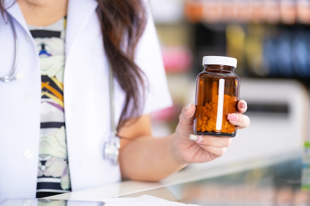 The pharmacist holds a bottle of medicine in the pharmacy