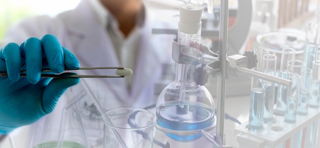 The pharmacist is using a tongs to bring the medicine to examined in the laboratory.