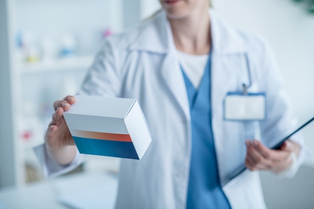 Pharmacist in a lab coat reading about a new medicine