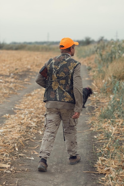 Pheasant hunter with shotgun walking through a meadow