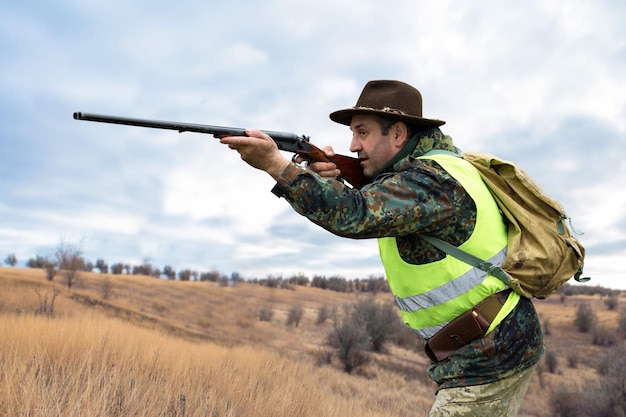 Pheasant hunters with shotgun walking through a meadow.