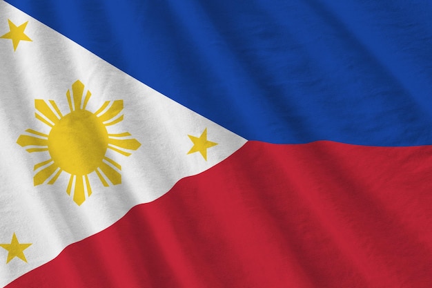 Philippines flag with big folds waving close up under the studio light indoors The official symbols and colors in banner