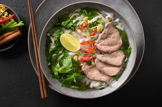 Pho Bo Soup with beef in bowl on black background Vietnamese cuisine