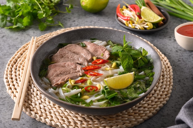 Pho bo soup with beef in gray bowl on gray vietnamese cuisine