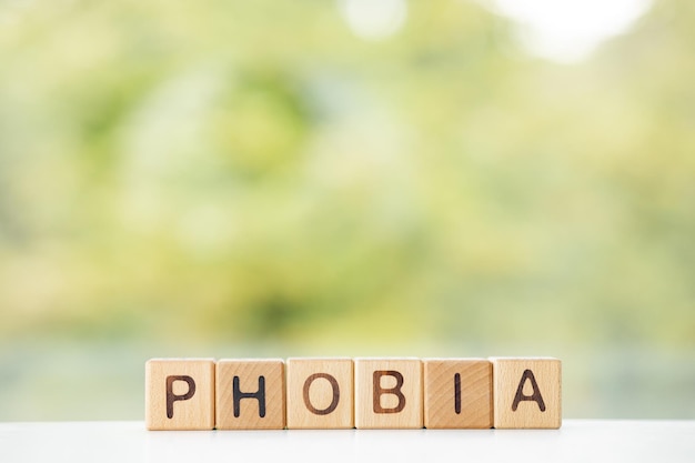 Phobia word is written on wooden cubes on a green summer background Closeup of wooden elements