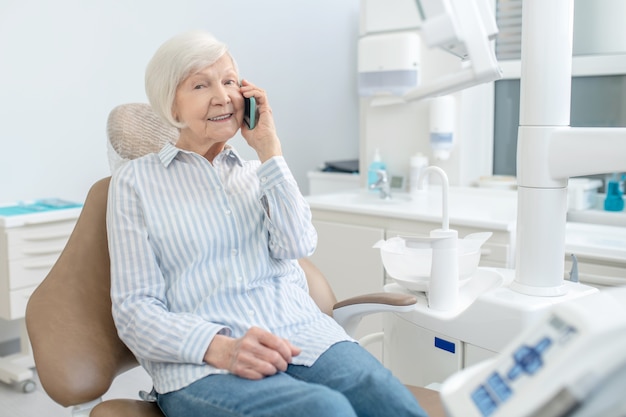 Phone call. Senior woman sitting at the dentists office and talking on the phone