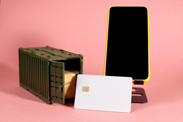 A phone a credit card and a box are on a pink background