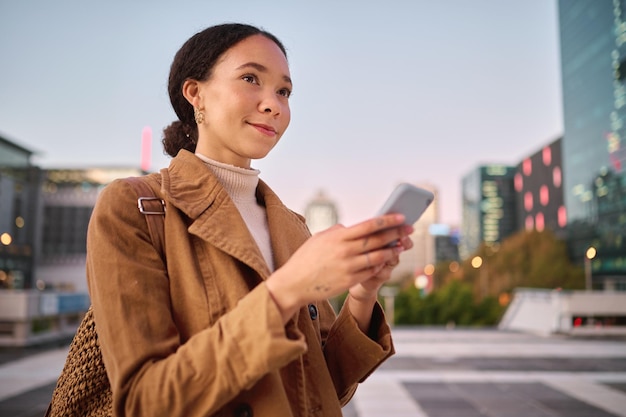 Phone social media and city with a business black woman walking on a street or road on her evening commute 5g mobile technology communication and networking with a female employee in an urban town