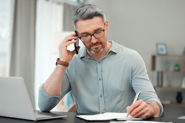 On the phone with his private banker Cropped shot of a handsome mature man making a phonecall while working on his finances at a desk at home