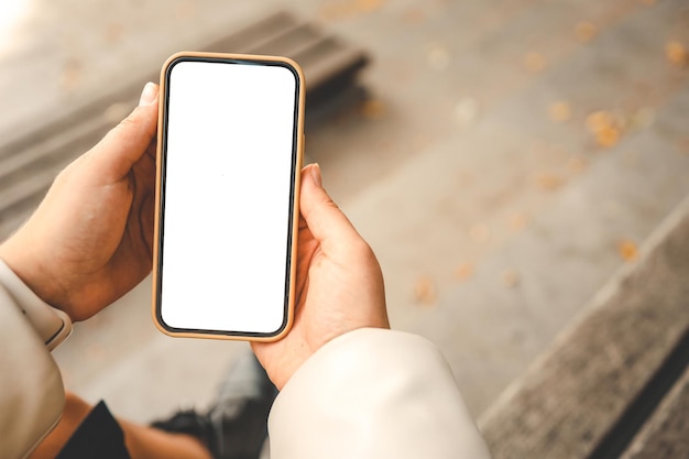 Phone with an isolated screen in hands on the street in the autumn park