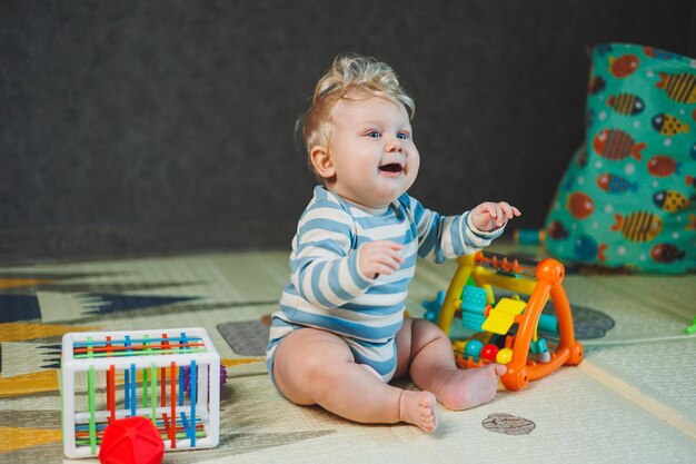 Photo of a 7monthold boy sitting on the floor and playing with toys The child is smiling and playing