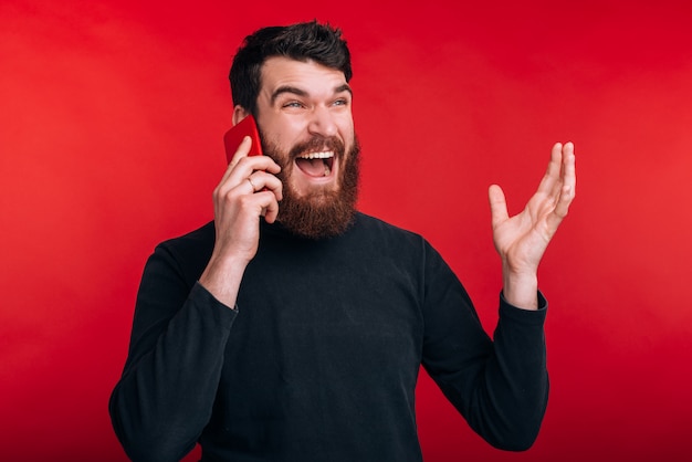 Photo of angry man screaming and talking on smartphone while standing over red space