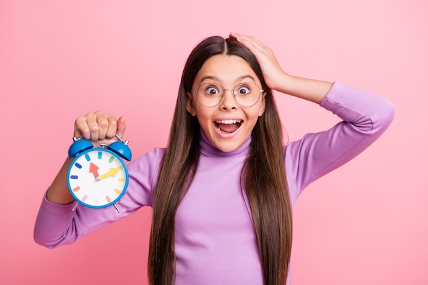 Photo of astonished little kid hold clock touch hand head isolated over pastel color background