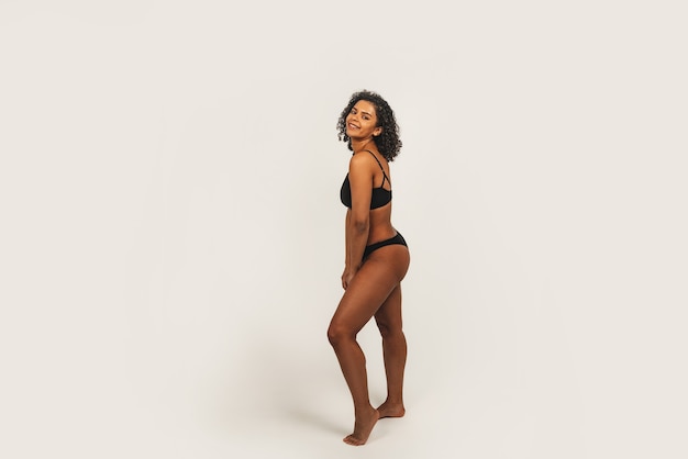 Photo of attractive black woman wears black underwear. Isolated over white background.