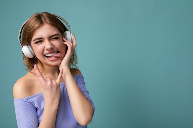 Photo of attractive emotional young blonde woman wearing blue crop top isolated on blue background