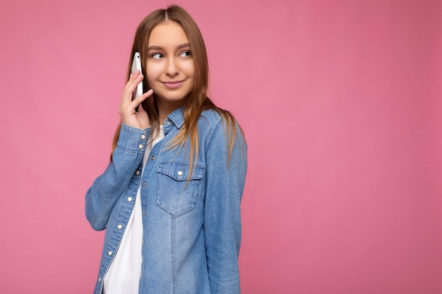 Photo of attractive positive young blonde woman wearing casual blue jean shirt isolated over pink