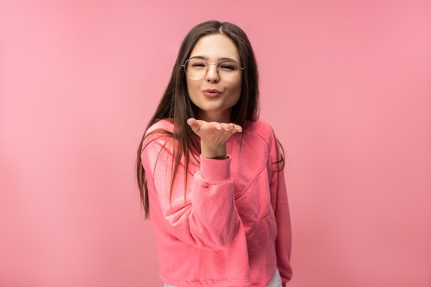 Photo of attractive young woman in glasses blows a kiss