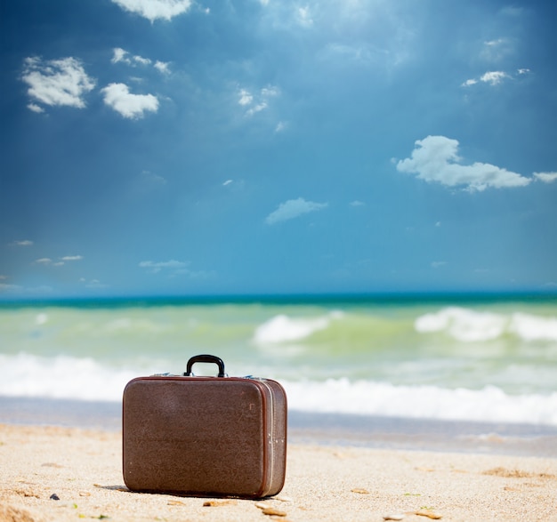 photo of beautiful brown suitcase on the wonderful sunny beach background