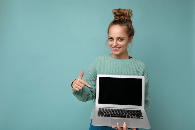 Photo of beautiful happy dark blond young woman with gathered curly hair  pointing