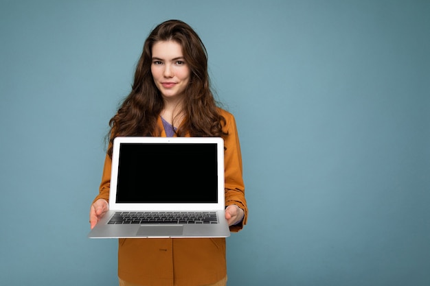 Photo of Beautiful satisfied young woman holding computer laptop looking at camera