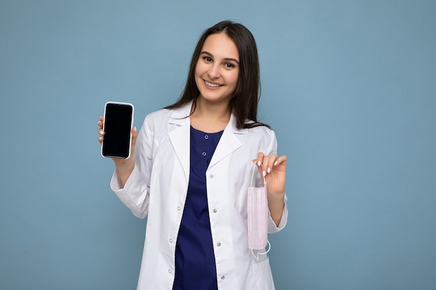 Photo of beautiful smiling young brunette woman good looking wearing white medical coat standing