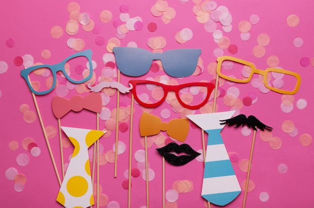 Photo booth props glasses, mustache, lips on a pink background flat lay. Birthday parties and weddings.