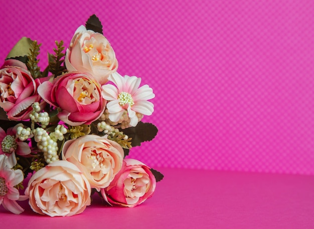 Photo of a bouquet of flowers beige gift in the form of a box on a pink background front view high