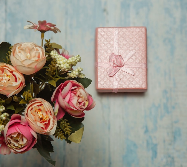 Photo of a bouquet of flowers pink gift in the form of a box on a blue background front view high