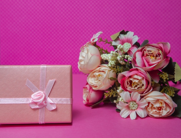 Photo of a bouquet of flowers pink gift in the form of a box on a pink background front view high