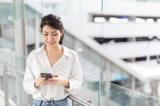 Photo business woman looking smartphone Open space loft office Panoramic windows background