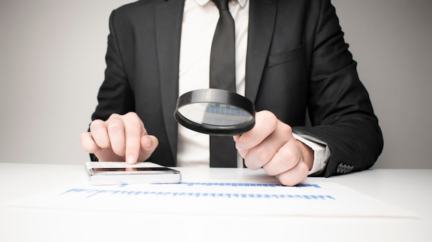 Photo Of Businessman Analyzing Bills With Magnifying Glass