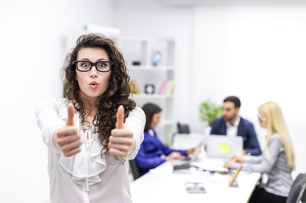 Photo of businesswoman showing thumbups in front of her team